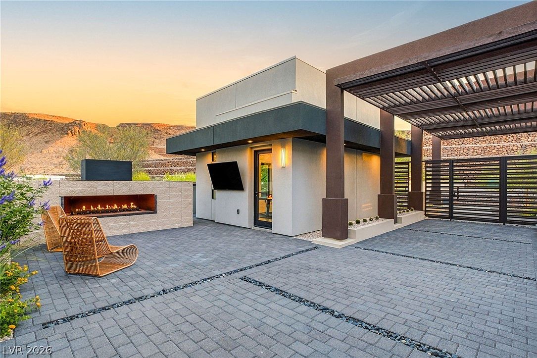 Outdoor patio at dusk with a long horizontal fire feature, woven chair, and the Black Mountain ridge beyond