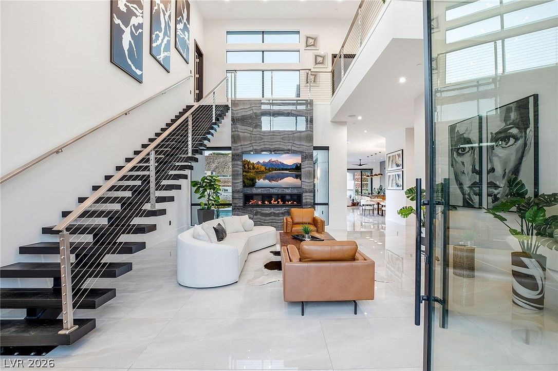 Great room interior with floating staircase, double-height ceiling, porcelain feature wall, and large modern art